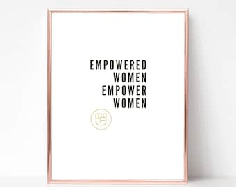 May include: A framed print with the text "EMPOWERED WOMEN EMPOWER WOMEN" in black lettering. A gold fist symbol is below the text.