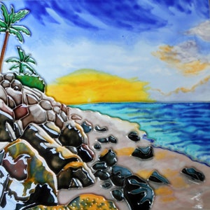 Könnte beinhalten: Eine handbemalte Keramikfliese, die eine tropische Strandszene mit Palmen, felsigen Klippen und einem blauen Meer mit einem gelben Sonnenuntergang im Hintergrund zeigt.