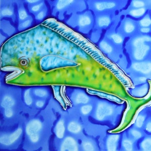 May include: A ceramic tile with a green, blue, and yellow painted image of a mahi-mahi fish swimming in a blue and white patterned background.