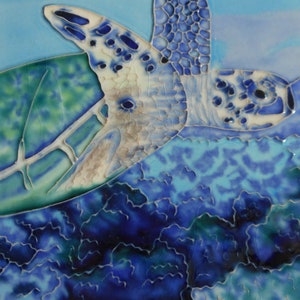 May include: A ceramic tile with a blue and white painted sea turtle swimming over a blue and green coral reef.