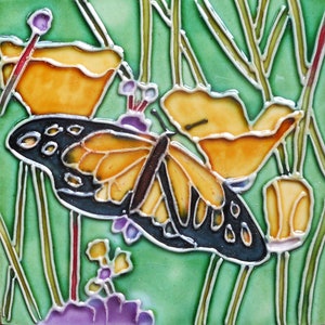May include: Square ceramic tile featuring a butterfly with orange and black wings, set against a backdrop of yellow flowers and green foliage. The tile has a glossy finish and is bordered by a green background with white outlines.