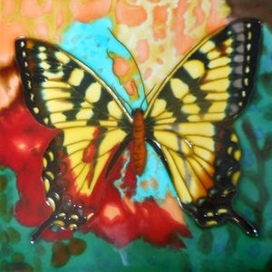 May include: A colorful ceramic tile featuring a detailed butterfly design. The butterfly has yellow wings with black markings and a brown body. The background includes red, turquoise, and orange hues, creating a vibrant and artistic piece.