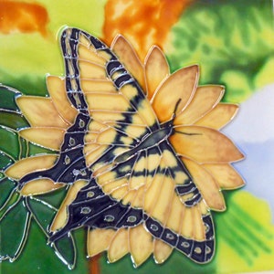 May include: A yellow and black butterfly with black and white markings on its wings is perched on a yellow flower with green leaves. The butterfly is painted on a ceramic tile.