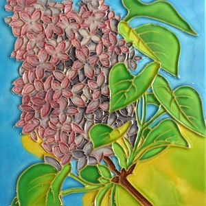 May include: A square ceramic tile featuring a detailed floral design of lilac blossoms. The flowers are a mix of pink and lavender, with green leaves and a brown stem against a blue and yellow background. The tile has a glossy finish.
