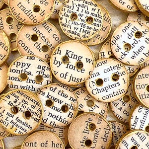 May include: A selection of circular, vintage-style buttons. Each button is made from paper with printed text and a gold-coloured edge. The buttons have two holes for sewing and are scattered across the image.