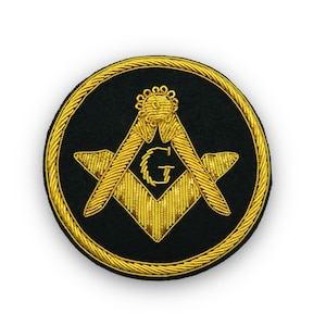 May include: A gold embroidered Masonic emblem on a black felt background. The emblem features a square and compass with a 'G' in the centre.