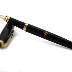 Könnte beinhalten: Ein schwarzer Stift mit goldenen Akzenten und einem goldenen Freimaurer-Symbol auf dem Schaft.