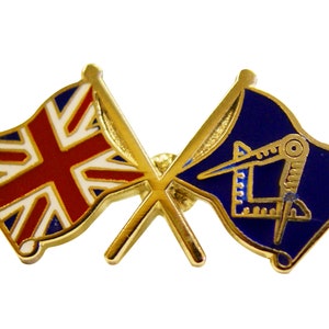 May include: A gold-coloured pin badge depicting two crossed flags. One is the Union Jack, the other a blue flag with Masonic symbols. This pin is likely a lapel badge or emblem.