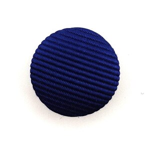 May include: A dark blue button with a textured surface. The button is round and has a diameter of approximately 1 inch.