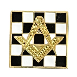May include: A gold-coloured Masonic symbol with a black and white chequered background. The symbol is a square and compass with a diamond in the centre.
