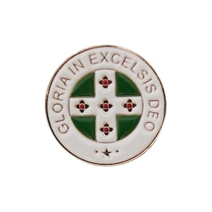 May include: A white enamel pin with a gold border and a green cross with four red four-pointed stars. The text "GLORIA IN EXCELSIS DEO" is written around the edge of the pin.