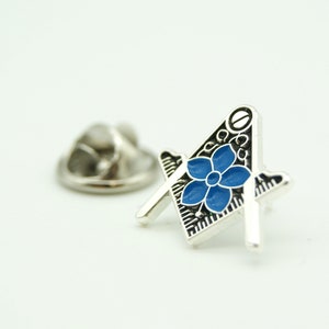 May include: Silver Masonic pin with a blue flower design. The pin has a safety clasp on the back.