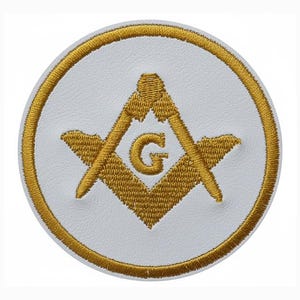 May include: A circular white patch with a gold embroidered border. The patch displays a gold embroidered Masonic symbol, comprising a square and compass with a letter "G" at the centre. The design is centrally positioned.