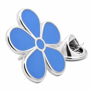 Puede incluir: Un broche de flor plateado con un centro de esmalte azul brillante. El broche presenta cinco pétalos y un centro circular, con un cierre de alfiler clásico. Adecuado para solapas, bolsos o sombreros.