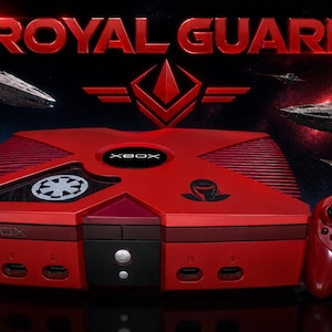 May include: Red Xbox console with matching controller, featuring a custom design with the text "ROYAL GUARD" and space battle imagery. The console has a black and red color scheme with a unique logo.