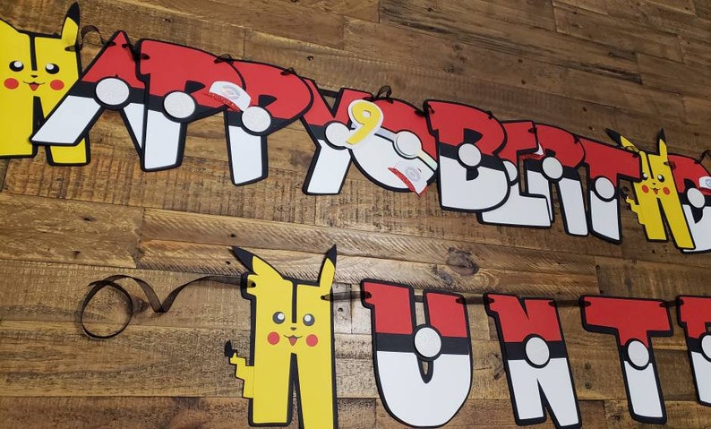 May include: A red, white, and black banner with the words "Happy Birthday" and "Hunt" in large letters. The letters are decorated with images of Pikachu and Pokeballs.
