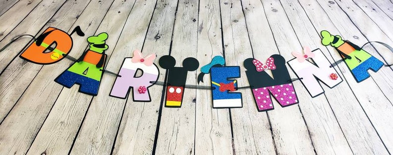 May include: A colorful Disney-themed banner with the name "DARITENA" spelled out in large letters. Each letter is decorated with a different Disney character, including Mickey Mouse, Minnie Mouse, Donald Duck, Goofy, and Pluto.