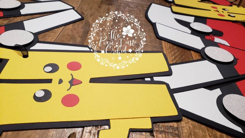 May include: A set of five yellow, red, white, and black felt cutouts of Pokemon characters. The characters are Pikachu, Charmander, Squirtle, Bulbasaur, and a trainer. The cutouts are designed to be used as party decorations or for crafts.