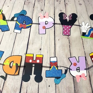 May include: A colorful Happy Birthday banner with Mickey Mouse and Minnie Mouse characters. The letters are decorated with glitter and each letter has a different character design.