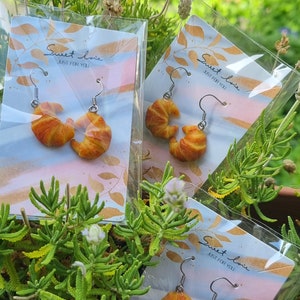 Puede incluir: Tres pares de pendientes en forma de croissant en tarjetas con el texto "Sweet love, Just for you".