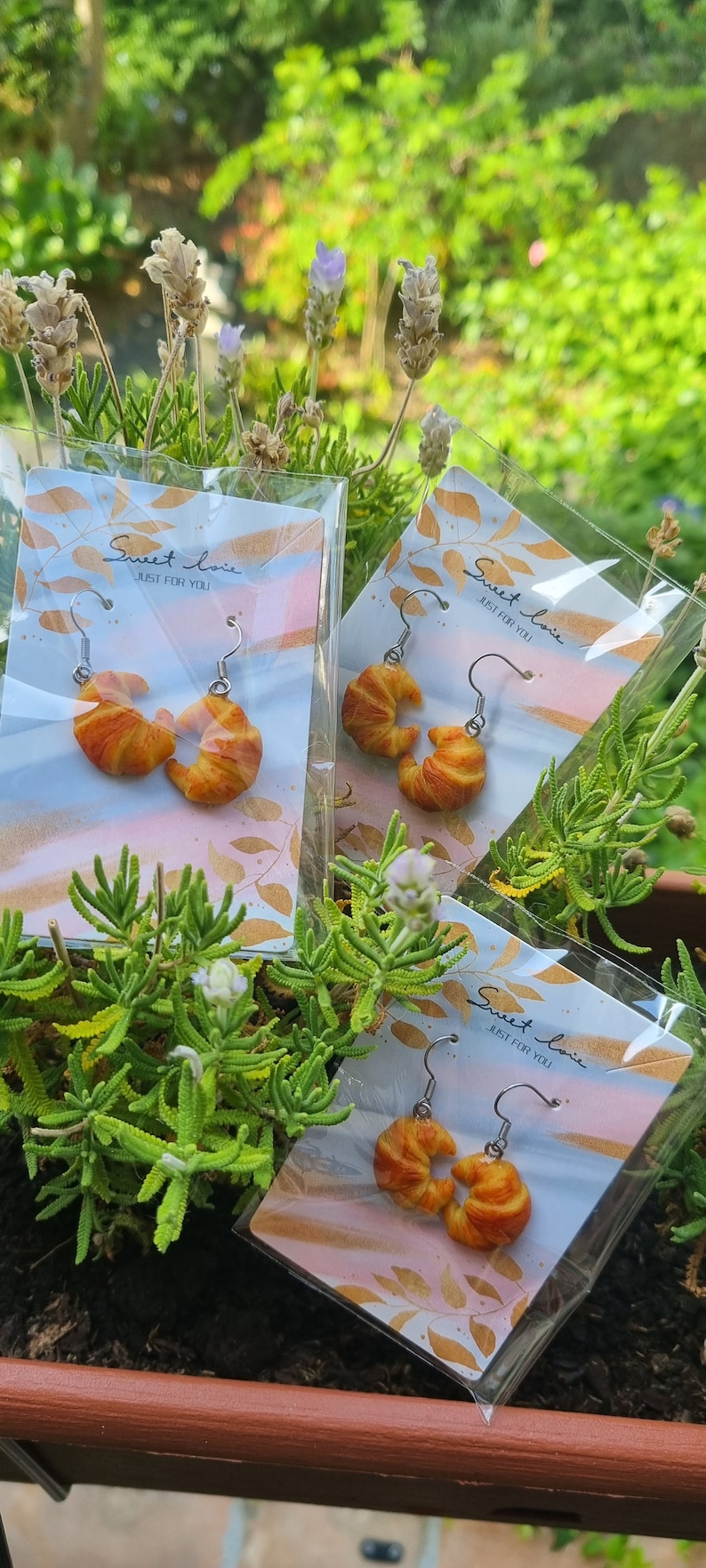 Puede incluir: Tres pares de pendientes en forma de croissant en tarjetas con el texto "Sweet love, Just for you".