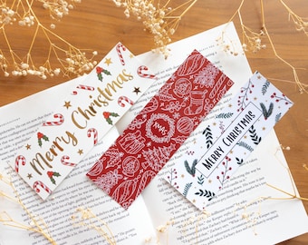 May include: Three Christmas-themed bookmarks with red, white, and gold designs. The bookmarks feature illustrations of candy canes, holly, wreaths, and the text "Merry Christmas".