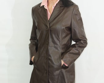 May include: A long brown leather coat with a button closure and pockets. The coat has a classic style and is made of high-quality leather.