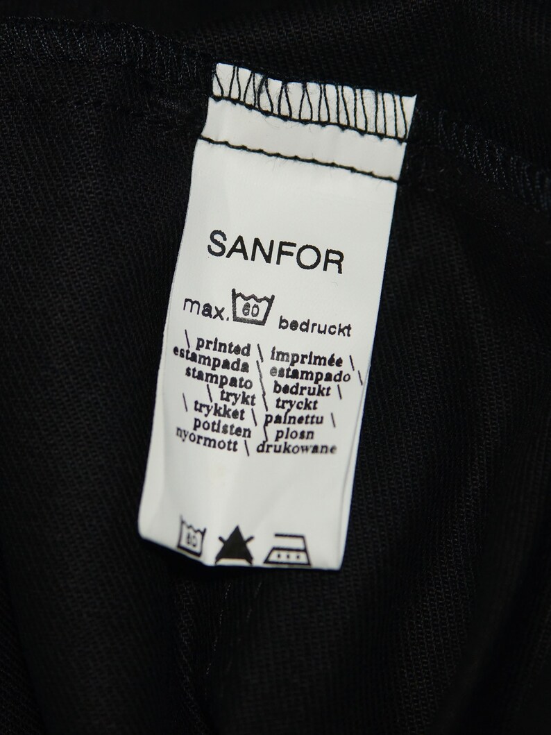 May include: White label with black text that reads "SANFOR" and includes a washing instruction icon. The label also includes the text "max. 60" and a list of words in multiple languages that translate to "printed".