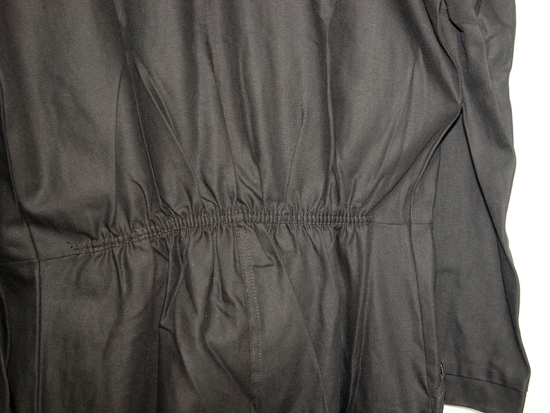 May include: Black jumpsuit with a drawstring waist.