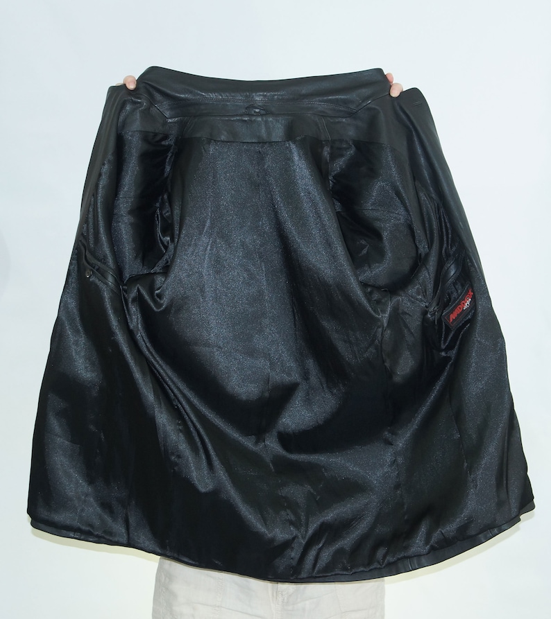 May include: Black leather jacket with a satin lining. The jacket has a zipper closure and a pocket on the inside.