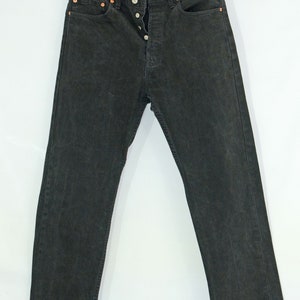 May include: A pair of black denim jeans with a button fly and five pockets.