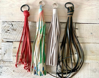 May include: Four different keychains with tassels. One is red, one is beige, one is brown and black, and one is multi-colored with a geometric pattern.