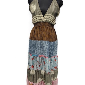 Könnte beinhalten: Ein ärmelloses Maxikleid mit tiefem V-Ausschnitt und elastischer Taille. Das Kleidungsstück besteht aus mehreren horizontalen Stoffbahnen in verschiedenen Farben wie Olivgrün, Braun, Blau und Rosa mit unterschiedlichen Mustern.