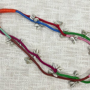 Könnte beinhalten: Eine mehrsträngige Halskette aus orangefarbenem, blauem, grünem und rosafarbenem Band mit weißen Muschelaccenten.