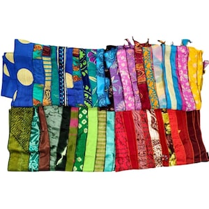 May include: A collection of colorful, patchwork fabric strips. The strips feature a variety of patterns and colors, including blue with yellow polka dots, floral prints, and stripes. The fabrics appear to be silk or a similar lightweight material.