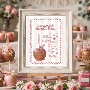 May include: A framed sign with a white and pink striped background featuring the text Caramel Apple Bar and instructions for making caramel apples. The sign is displayed on a wooden easel surrounded by caramel apples and jars of toppings.