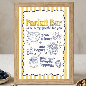 May include: A framed sign with the text "Parfait Bar" and instructions for making a parfait. The sign has a yellow and white striped background and blue and yellow accents. A bowl of blueberries, a honey dipper, and granola are in the foreground.