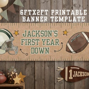 May include: A 6ft x 2ft printable banner template with a tan background featuring a football helmet, a football, and two yellow stars. The text reads "JACKSON'S FIRST YEAR DOWN" in green letters. The banner has a ruler-style border along the top and bottom.