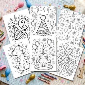 May include: Several black and white coloring pages with birthday designs, such as balloons, party hats, and cakes. One page features the text "IT'S FUN TO BE ONE". Colouring pencils and crayons are arranged around the pages.