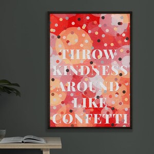 Könnte beinhalten: Gerahmter Kunstdruck mit dem weißen Schriftzug "THROW KINDNESS AROUND LIKE CONFETTI" vor einem Hintergrund aus roten, orangefarbenen und rosa Kreisen. Der Rahmen ist schwarz.