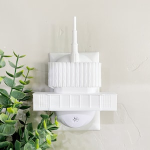 May include: White plastic nightlight shaped like a temple with a spire on top. The nightlight plugs into a standard electrical outlet.