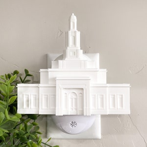May include: White plastic nightlight shaped like a temple with a spire on top. The nightlight plugs into a standard electrical outlet.