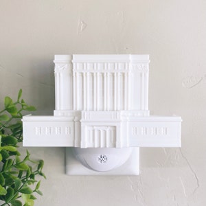May include: White plastic nightlight shaped like a temple with a white electrical outlet plug.