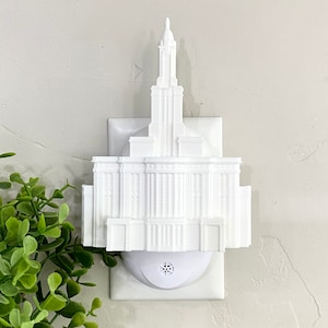 May include: White plastic night light shaped like a temple, plugged into a standard electrical outlet.