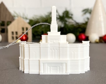 Op de afbeelding: Witte 3D-geprinte ornament van een kerkgebouw met een toren. De ornament heeft een zilveren touwtje om op te hangen.