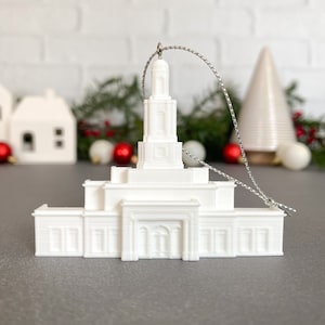 May include: White ceramic ornament shaped like a temple with a silver string for hanging.