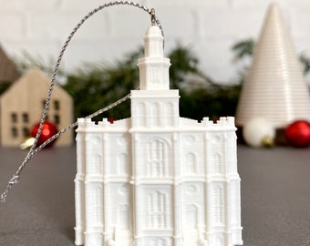 Op de afbeelding: Witte 3D-geprinte ornament van een kerkgebouw met een toren. De ornament heeft een zilveren touwtje om aan een kerstboom te hangen.