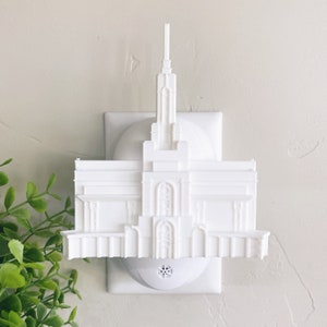May include: White plastic nightlight shaped like a temple. The nightlight plugs into a standard electrical outlet.