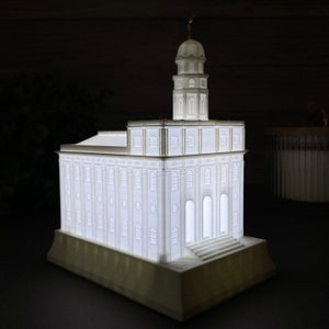 Op de afbeelding: Een wit 3D-geprint model van een tempel met een toren en een basis. Het model is van binnenuit verlicht, waardoor een zachte gloed ontstaat.