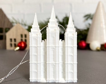 May include: White 3D printed ornament of the Salt Lake Temple, a famous Mormon temple in Utah. The ornament has a string for hanging on a Christmas tree.